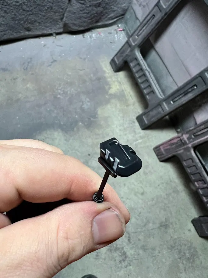 Small black coated part held in hand